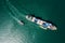 Container ship and tugboat dragging in green sea aerial top view