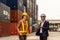 Container yard manager talking to female foreman about custom document of the goods inside the warehouse among containers