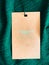 Contains recycled polyester fashion label tag, sale price card on luxury emerald green fabric background, shopping and retail