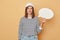 Contemplation before deciding. Questioning with a blank mind. Puzzled woman wearing baseball cap and striped shirt holding empty