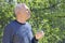 Contemplative elderly man with a glass of water in his hand in nature