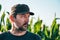 Contemplative farmer in corn field. Farm worker wearing trucker\'s hat posing in agricultural plantation