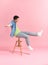 Contemplative guy dressed sitting on a stool on a pink background in the studio