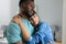 Contemplative multiracial young couple embracing while standing together at home