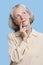 Contemplative senior woman in casuals with hand on chin against blue background