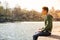 Contemplative teenage boy sitting beside river