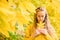 Contemplative young pretty female is holding yellow leaf on a yellow leaves background in the city park in golden fall season