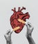 Contemporary art collage. Human hands and drawn red human heart over light background. Concept of care, health, medicine