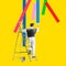 Contemporary art collage. Talented, creative man standing on ladder and making colorful paintings on yellow background