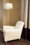 Contemporary beige comfortable armchair with lamp. Furniture