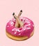 Contemporary collage, creative artwork of female hands sticking out pink donut isolated over pink background