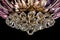 Contemporary gold chandelier isolated on black background. Crystal chandelier decorated Pink crystals close-up