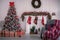 Contemporary interior with Christmas decorations in evening. White fir tree decorated with red balls, gift boxes and fireplace