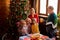 Contemporary large multi-generation family sitting by served festive table on Christmas day