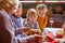 Contemporary large multi-generation family sitting by served festive table on Christmas day