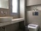 Contemporary style interior of small modern bathroom tiled gray pebble stone with window, bowl sink, hidden wall hung toilet