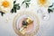 Contemporary table setting with peony flowers and golden utensils on white table. Modern trendy flat lay, top view on dinner table