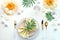 Contemporary table setting with peony flowers and golden utensils on white table. Modern trendy flat lay, top view on dinner table