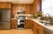 Contemporary upscale home kitchen interior with cherry wood cabinets, quartz countertops, sustainable recycled linoleum floors &