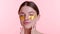 Content Caucasian Woman with Gold Eye Patches on Pink Background