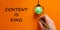 Content is king symbol. Businessman writing words `Content is king`, isolated on beautiful orange background. Light bulb icon.