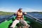 Contented bearded man in a life jacket rowing with oars on a boat and enjoying the beautiful scenery. Active lifestyle