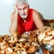A contented gray-haired man at a table with mushrooms