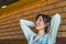 Contented happy young brunette woman stretching her arms in cafe