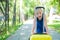 A contented little girl in a blue dress is standing alone in the street with a yellow suitcase and waiting for her