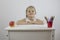 A contented little girl is sitting at her desk with pencils and a ripe apple