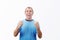 Contented middle aged man keeps fists tight raised up, lookingto camera with positive emotion, isolated on white background.