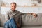 Contented Senior Man Sitting On Sofa Relaxing At Home