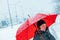 Contented woman talking on mobile phone under umbrella in snow