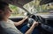 Contented young man driving car confident. Teenager driver enjoying the ride on the city streets, keeps hands on the steering