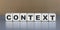 CONTEXT word on wooden cubes on a beautiful gray background
