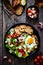 Continental breakfast - sunny side up eggs on white mushrooms, onion and greek salad on wooden table