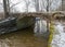 A continuous boulder stone bridge with a brick used for masonry, early spring, bare trees, snow plan on the ground, Stone arch