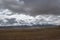 Continuous snow mountains and beautiful plateau meadows under dark clouds