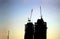 Contours of tower cranes above the high constructing tower buildings against early morning sky in the sunrise