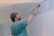 Contractor painter man hands with painting the wall the corners edge with brush