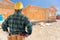 Contractor Standing Outside Construction Framing of New House.