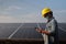 A contractor wearing a yellow helmet and mask on a solar panels background