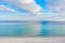 Contrast photo of the sea and cloudy sky. Clouds reflected in water. Footprints on coastal sand