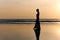 Contrast silhouette of a young slender woman against the background of a Sunny sunset, the sea and the sandy beach.