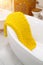contrasting yellow knitted blanket lies in free- standing bathtub in the bathroom