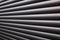 Contrasty abstract close up filled frame background wallpaper shot of grey window blinds with rays of light shining through and