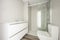 Conventional white wash basin, glass-enclosed shower, tiled floor imitating wood