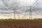 Converging high voltage cables and steel pylons in an agricultural landscape