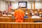 A convict in an orange suit speaks in the courtroom.