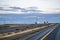 Convoy of different big rigs semi trucks with semi trailers driving on the divided straight highway road at twilight